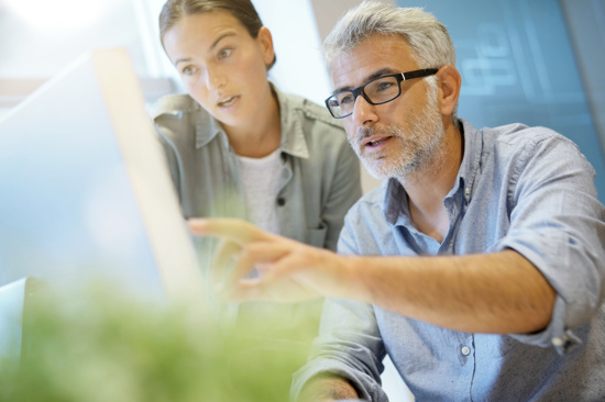 Man pointing at computer, showing something to a female colleague